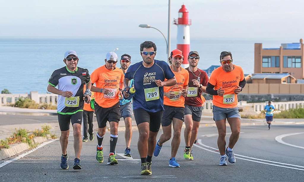 Corredores participantes de la Media Maratón Valparaíso con el Faro Punta Ángeles detrás de ellos