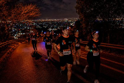 Corredores subiendo el Cerro San Cristóbal de noche con linternas frontales en sus cabezas