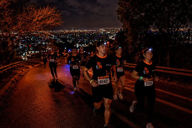 Corredores subiendo el Cerro San Cristóbal de noche con linternas frontales en sus cabezas