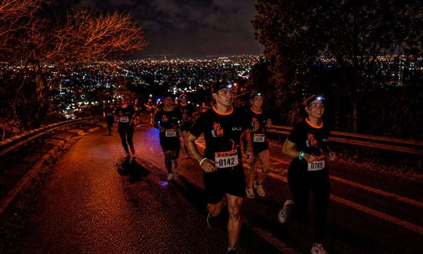 Corredores subiendo el Cerro San Cristóbal de noche con linternas frontales en sus cabezas