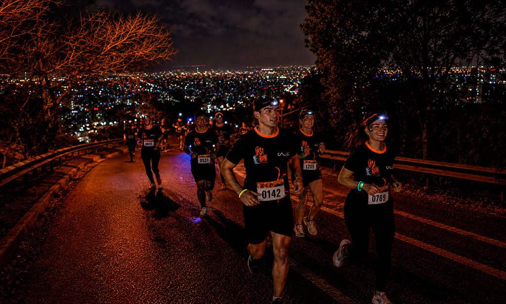 Corredores subiendo el Cerro San Cristóbal de noche con linternas frontales en sus cabezas